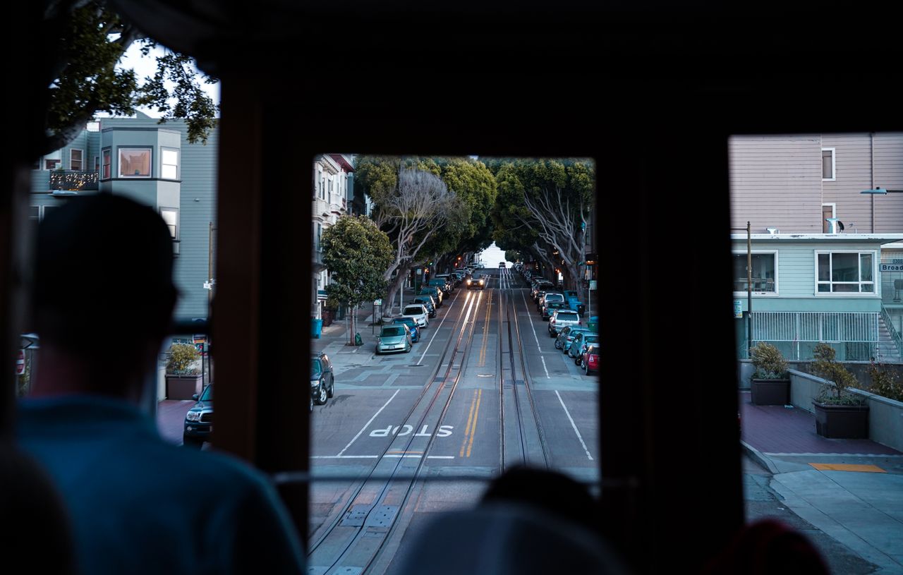 about-img A scenic view of San Francisco streets from inside a moving cable car, highlighting urban transportation.